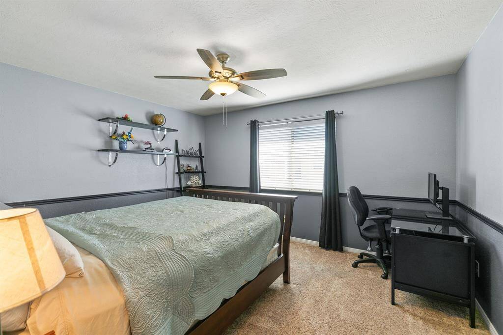 Another view of the 2nd bedroom. It features a ceiling fan, two-tone grey paint and a nice view of the backyard. The two display shelves will stay.