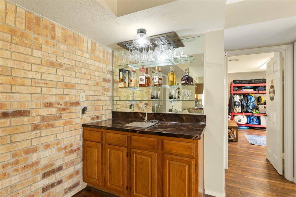 The wet bar features glass shelves for your glassware along with drawers and cabinets below for the storage of your bar essentials. The brick accent wall behind the fireplace enhances this space and adds visual appeal.