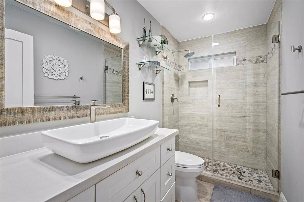 The bathroom features a modern glass stand-in shower, offering a clean and contemporary touch.