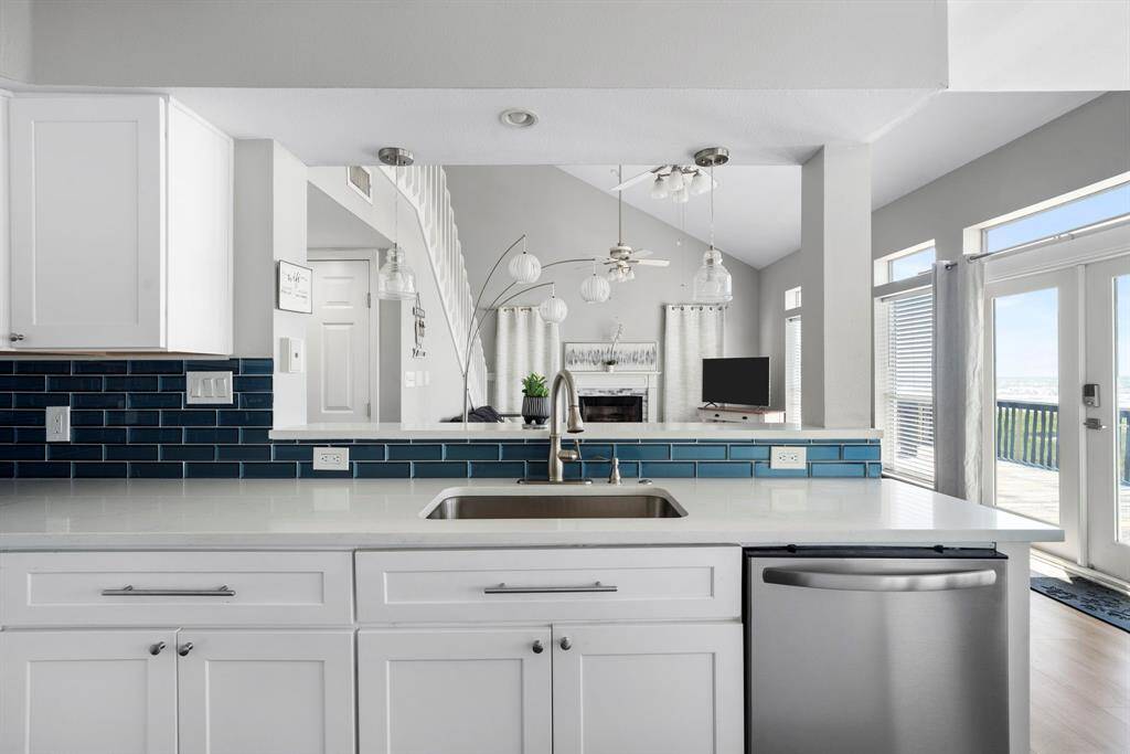 Crisp white cabinetry, designer backsplash, and a large central island with deep sink overlook the living space and vaulted ceilings.