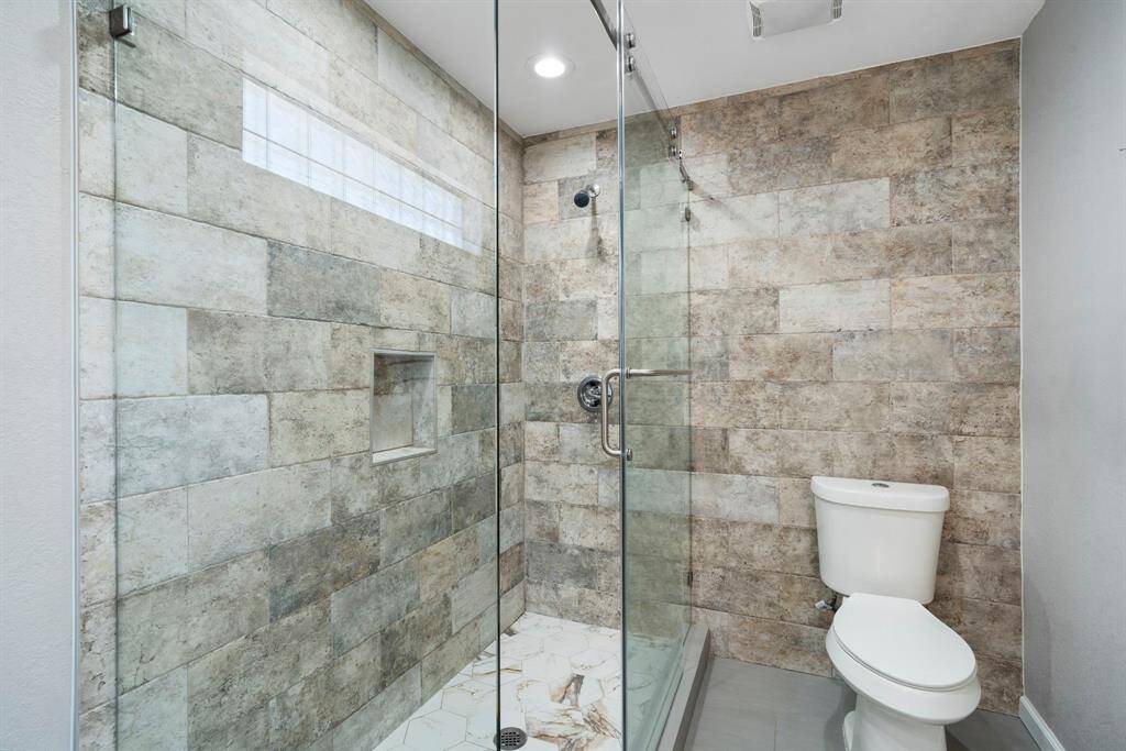 Stylish and functional bathroom complete with a frameless glass shower, elegant tilework, and dual sinks—ideal for shared use.