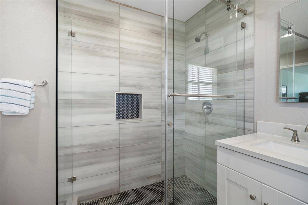 Striking walk-in shower with floor-to-ceiling tile, frameless glass doors, and a rainfall showerhead—designed for both style and comfort.