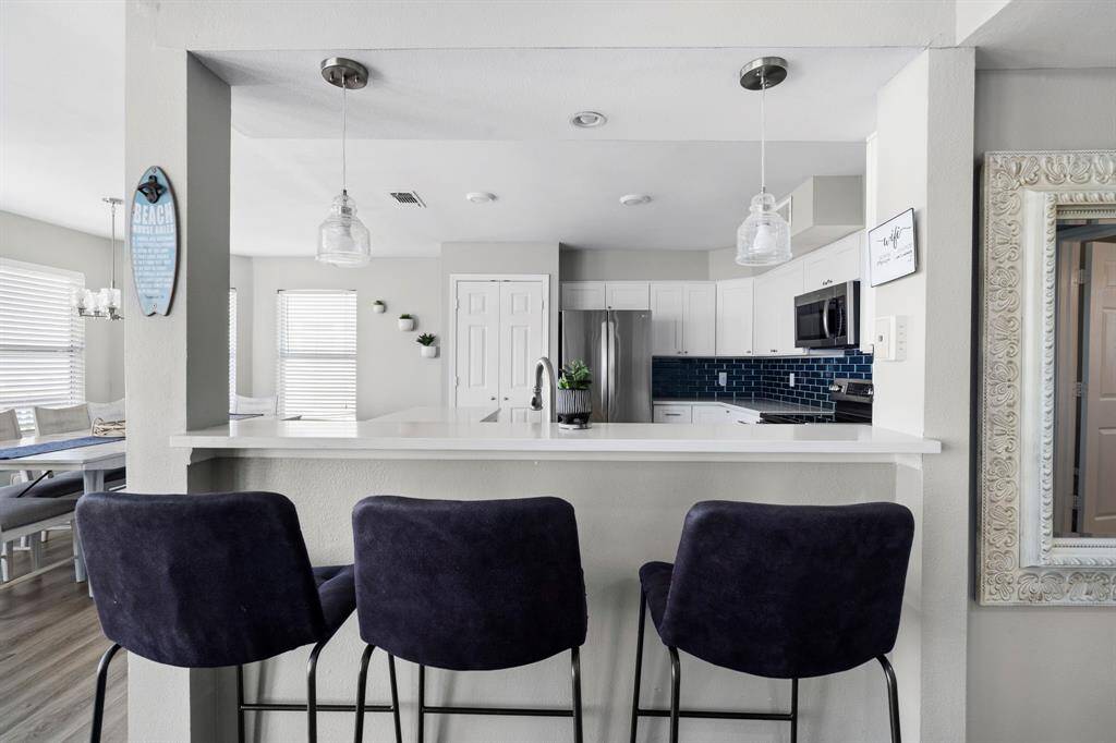 Spacious island with quartz countertop and pendant lighting, perfect for casual dining or gathering with guests.