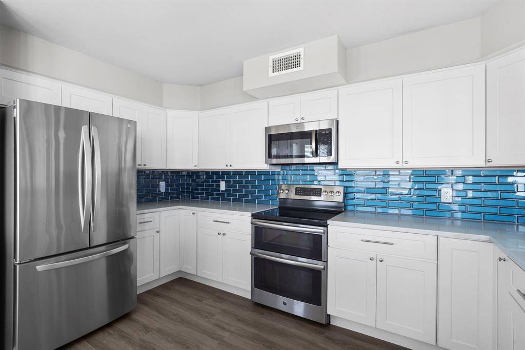 Thoughtfully remodeled kitchen with shaker cabinets, upgraded appliances, and stylish blue tilework for a modern beachy vibe.