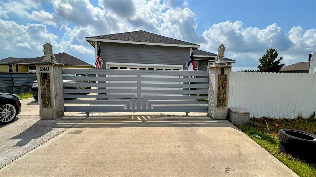 Partial view of the front home with a gated driveway, featuring a sleek horizontal slat design. The property includes a garage and a fenced yard, providing privacy and curb appeal.