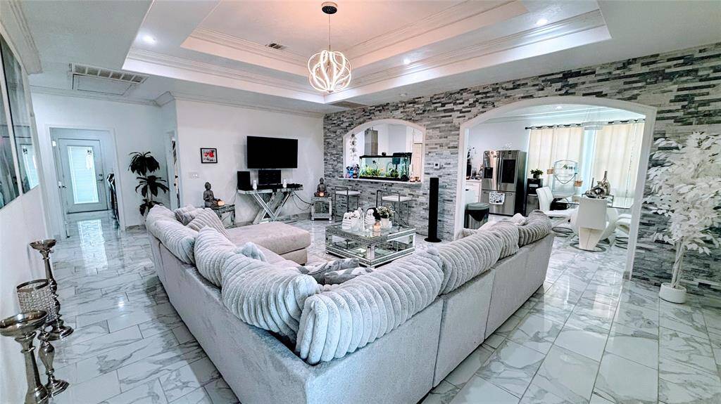 This spacious living area features a modern design. The room boasts a stylish coffered ceiling with a contemporary light fixture.