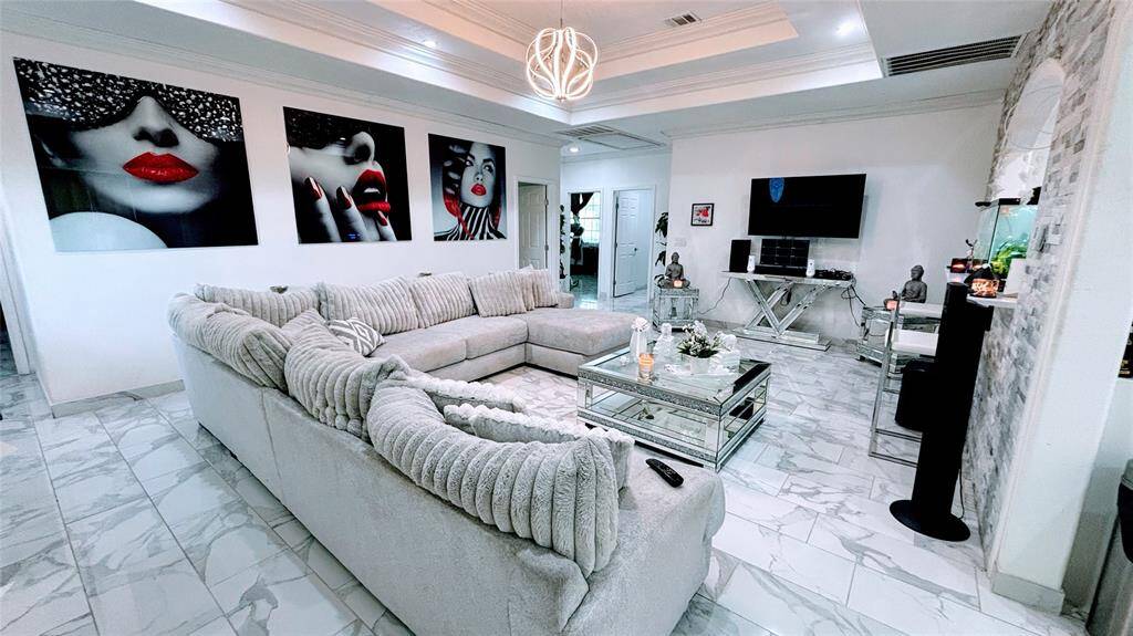 This spacious living area features a modern design. The room boasts a stylish coffered ceiling with a contemporary light fixture.