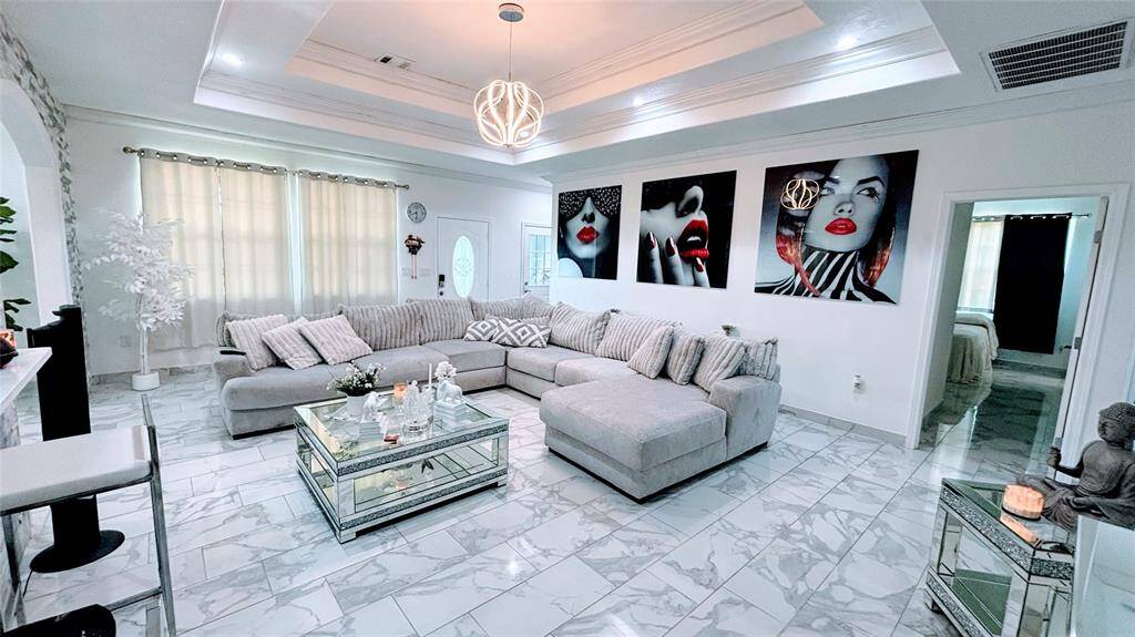 This spacious living area features a modern design. The room boasts a stylish coffered ceiling with a contemporary light fixture.