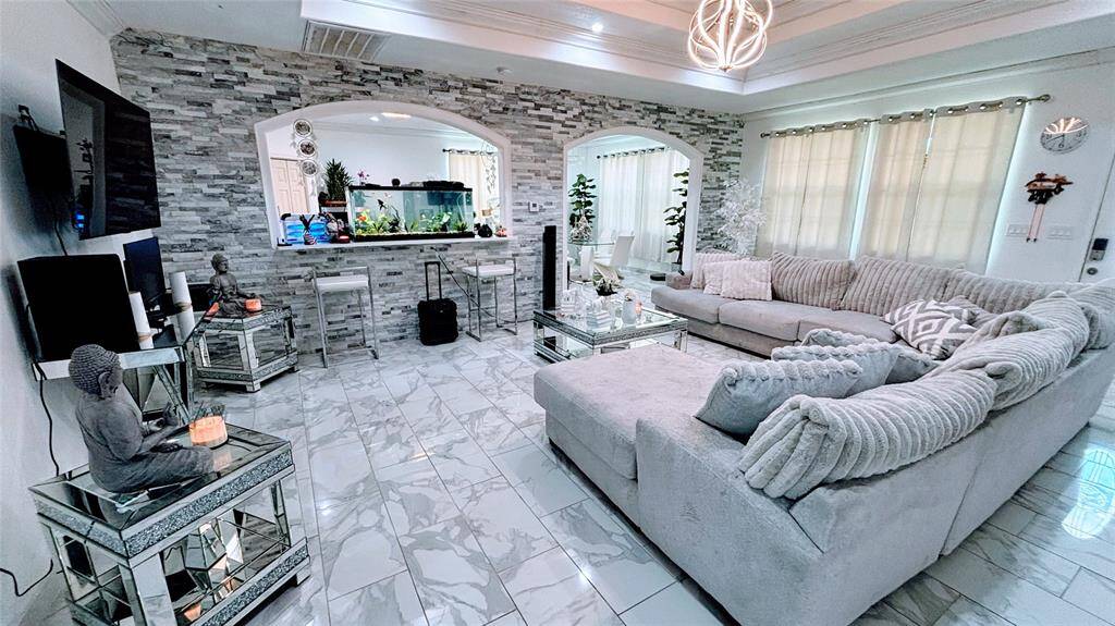 This spacious living area features a modern design. The room boasts a stylish coffered ceiling with a contemporary light fixture.