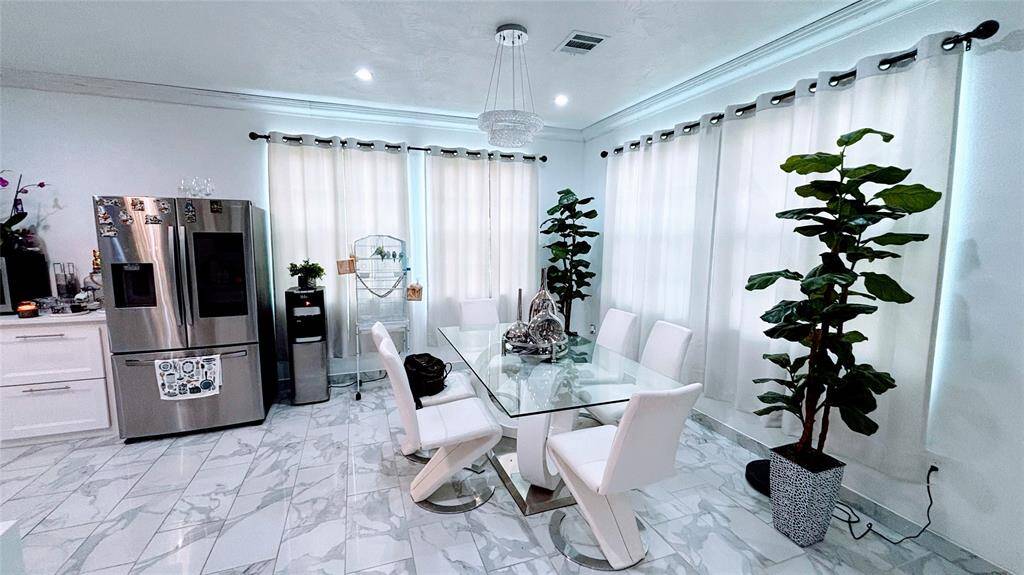 Modern dining area features elegant marble flooring. Large windows with light curtains allow plenty of natural light.