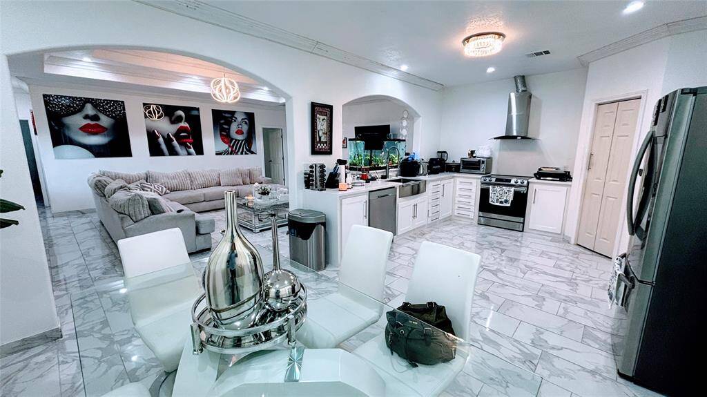 Modern dining area features elegant marble flooring. Large windows with light curtains allow plenty of natural light.