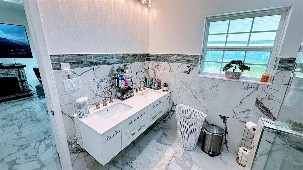 A double-sink vanity with sleek fixtures, and a large window for natural light. It offers a clean, contemporary look with ample counter space and storage.
