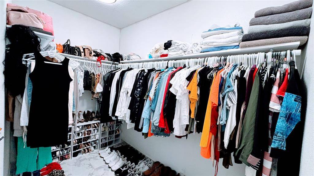 Spacious walk-in closet with organized shelving and hanging space. It features ample room for clothing, shoes, and accessories, with a tidy arrangement of folded towels on the top shelf.