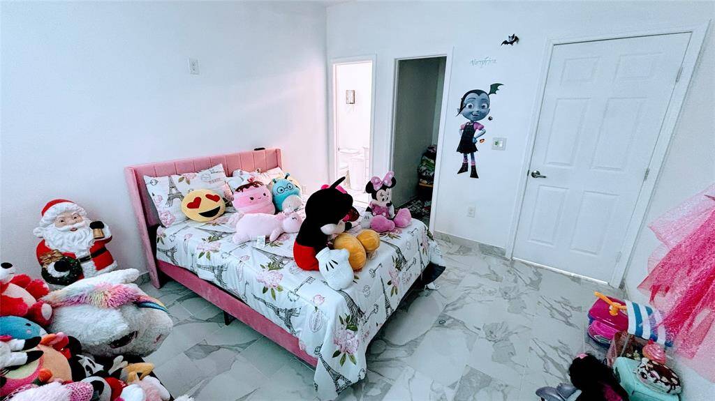 Cozy bedroom with tiled flooring and ample natural light. It features a single bed with a playful theme, perfect for a child's room.