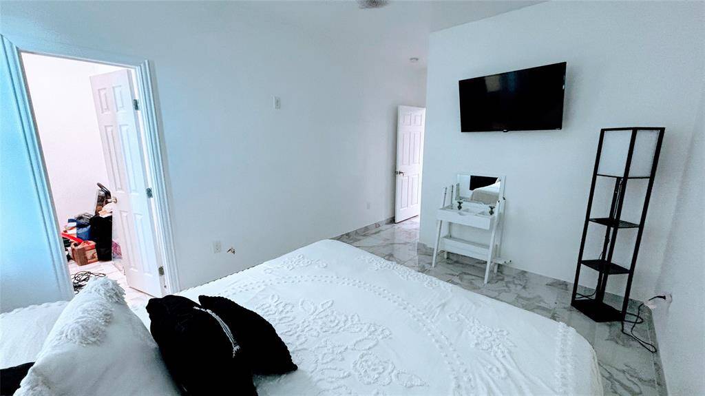 This bedroom features a clean, modern design with white walls and marble tile flooring.