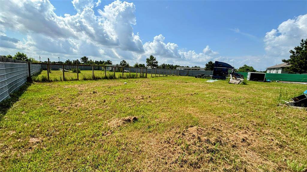 Spacious, grassy lot enclosed by metal fencing ideal for new construction or outdoor activities.