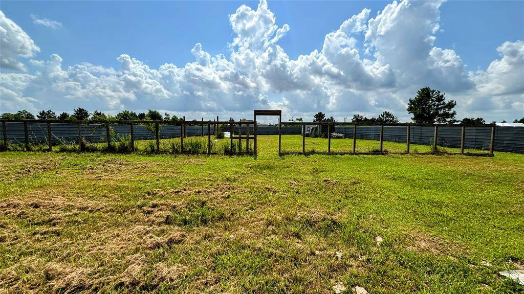 Spacious, grassy lot enclosed by metal fencing ideal for new construction or outdoor activities.