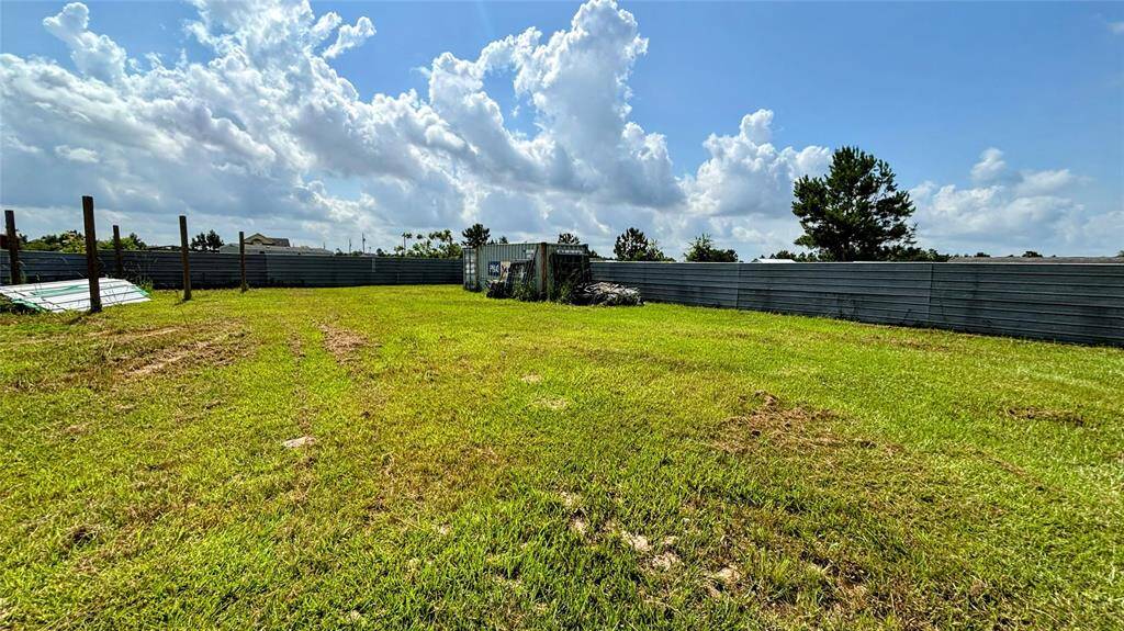 Spacious, grassy lot enclosed by metal fencing ideal for new construction or outdoor activities.