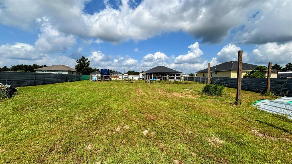 Spacious, grassy lot enclosed by metal fencing ideal for new construction or outdoor activities.