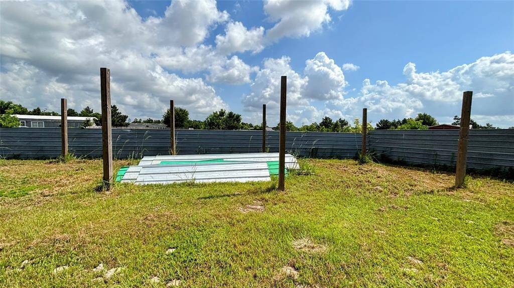 Spacious, grassy lot enclosed by metal fencing ideal for new construction or outdoor activities.