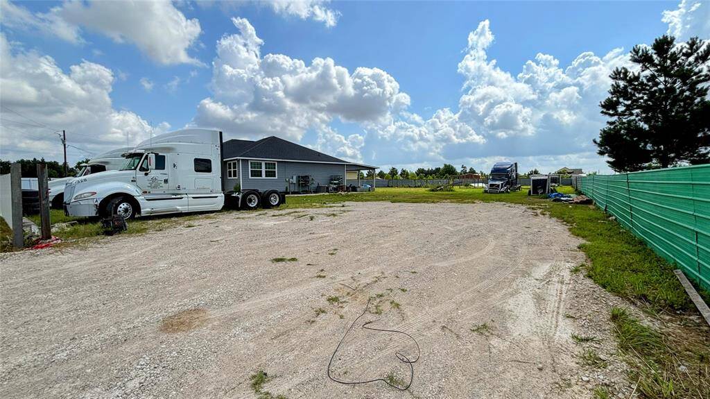 Spacious gravel lot fenced area, ideal for parking large vehicles. The surroundings are open.