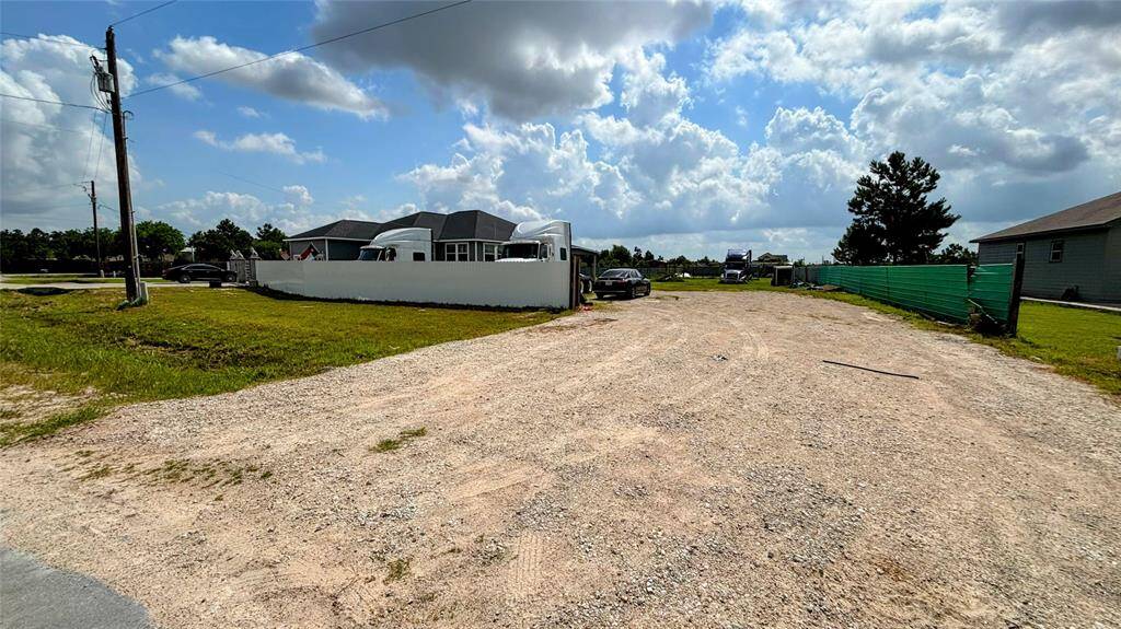 View of  the property with a gravel driveway, ample parking space, and a fenced yard.