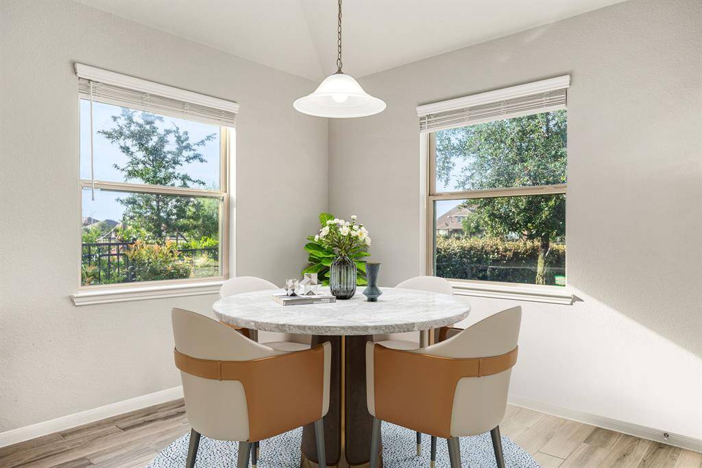 This lovely breakfast area is perfect for starting the day out on the right foot.  This space showcases neutral paint, high ceilings, hanging pendant light, recessed lighting, large windows adding to the ample natural light in the kitchen, and wood look tile flooring.