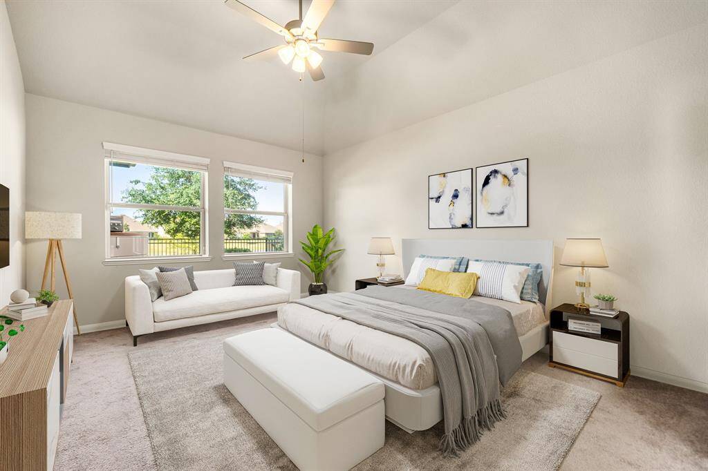 This spacious primary bedroom boasts high vaulted ceilings and large windows that fill the room with natural light and offer scenic outdoor views. Soft carpeting adds warmth and comfort, while the neutral color palette provides a serene and relaxing atmosphere. A ceiling fan enhances airflow and comfort year-round.