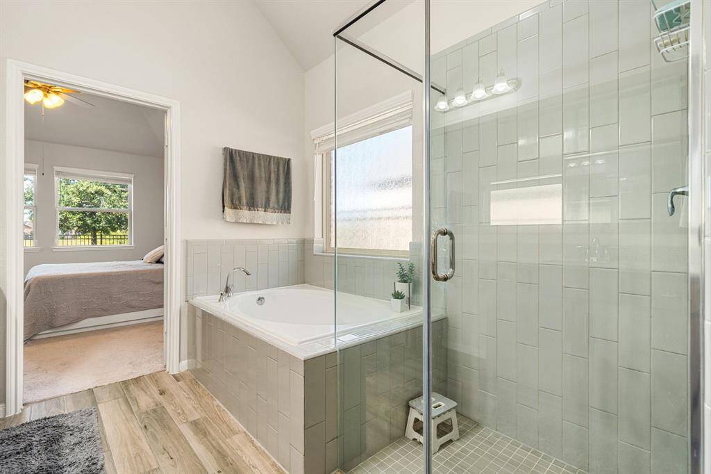 This additional view of the primary bath showcases a spa like walk-in shower with tile surround and a separate garden tub perfect for soaking after a long day.