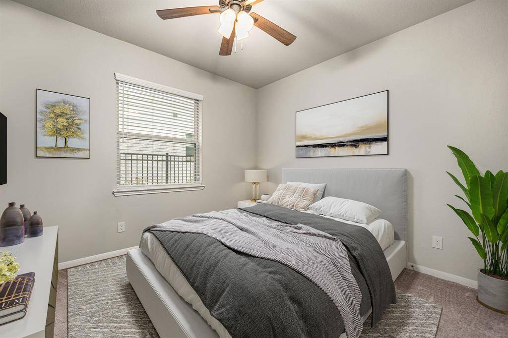 Secondary bedroom features plush carpet, neutral paint, dark stained ceiling fan with lighting and a large window with privacy blinds.