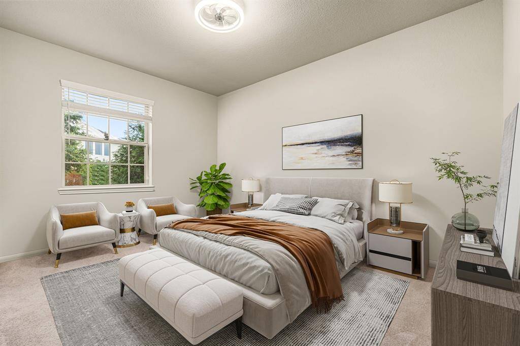 Secondary bedroom features plush carpet, neutral paint, dark stained ceiling fan with lighting and a large window with privacy blinds.