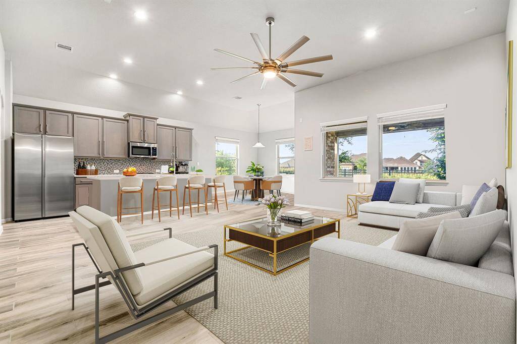 Step into this beautifully designed open-concept living space, where natural light pours in through large windows, highlighting the elegant wood-look tile flooring and soaring ceilings. The chef’s kitchen features sleek stainless steel appliances, Quartz countertops, a stylish mosaic backsplash, and a spacious island with bar seating—perfect for entertaining.