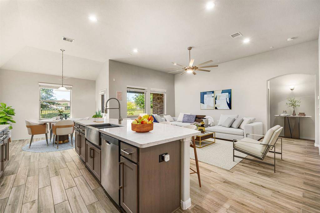This elegant open-concept layout showcases stylish wood-look tile flooring, soaring ceilings, and a light, neutral palette that enhances the spacious feel. The chef’s kitchen is thoughtfully appointed with a generous island, sleek Quartz countertops, a deep farmhouse sink, and abundant cabinet space. Graceful archways and recessed lighting lend character and continuity, offering a seamless blend of functionality and sophistication throughout the home.