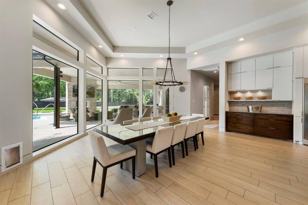 Flooded with natural light, the dining area offers serene views of the pool and backyard through expansive windows, perfectly blending indoor elegance with outdoor tranquility.