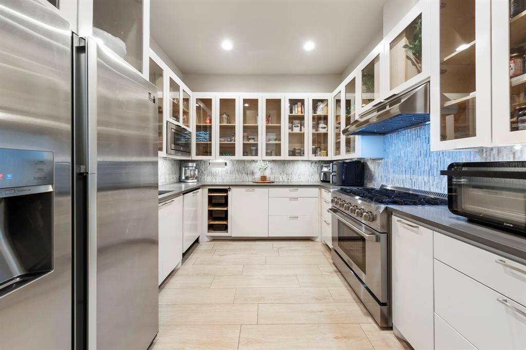Just off the main kitchen, a spacious walk-in pantry doubles as a chef’s prep kitchen, complete with a refrigerator, gas range and oven, dishwasher, sink, and abundant storage.