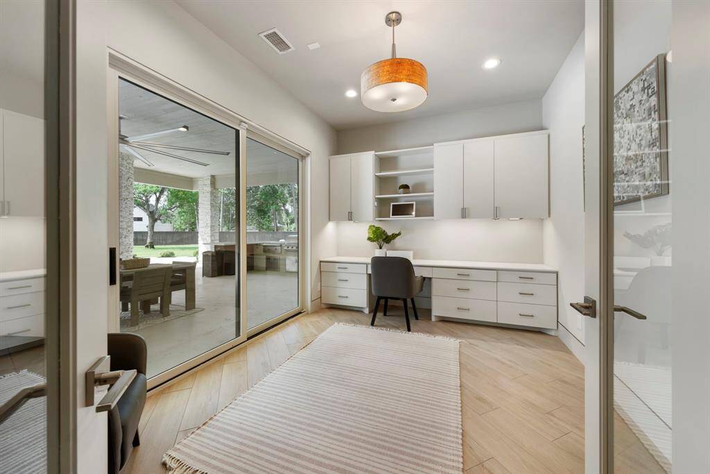 Bathed in natural light and framed by serene backyard views, this stylish home office features built-in cabinetry, sleek finishes, and seamless indoor-outdoor access for ultimate inspiration and productivity.