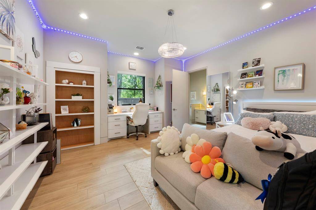 Secondary bedroom features a built-in desk and private en-suite bath. A hidden bookshelf reveals a walk-through closet that connects to the adjoining bedroom—perfect for siblings or a shared space setup.