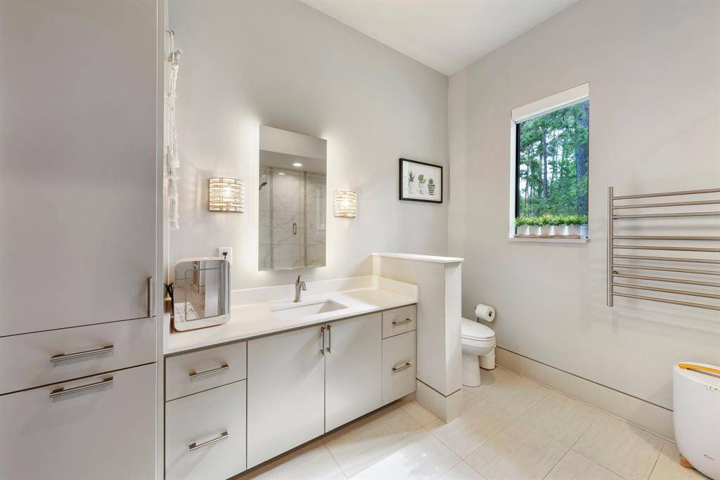 Almost identical en-suite bath showcases a soothing color palette, sleek countertops, generous storage, and a stylish shower/tub combination.