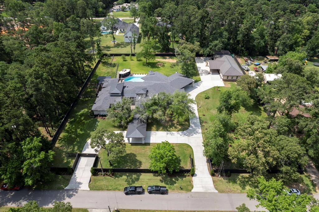 Aerial view of a private, fully fenced estate featuring a resort-style pool, circle drive, expansive lawns, and a detached guest house or workshop—ideal for multi-use living on over two acres.