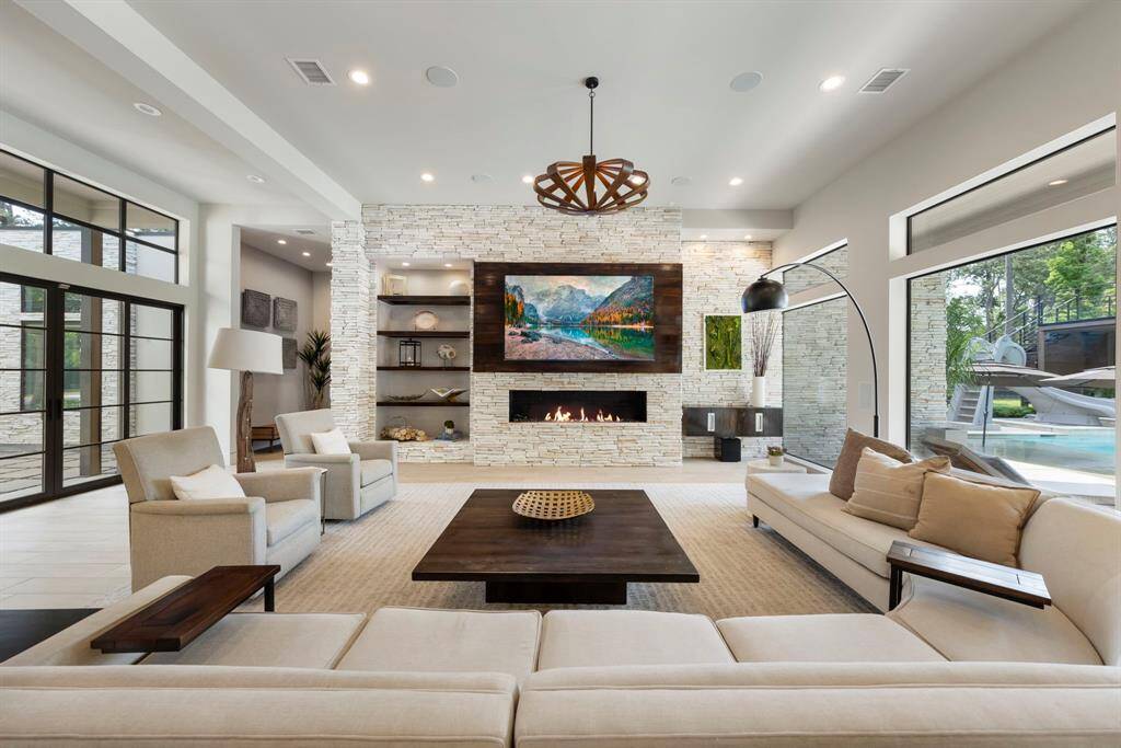 The family room blends crisp architecture with cozy textures, anchored by a striking stone fireplace and walls of glass that open to a backyard oasis. Surround sound for ultimate entertainment.