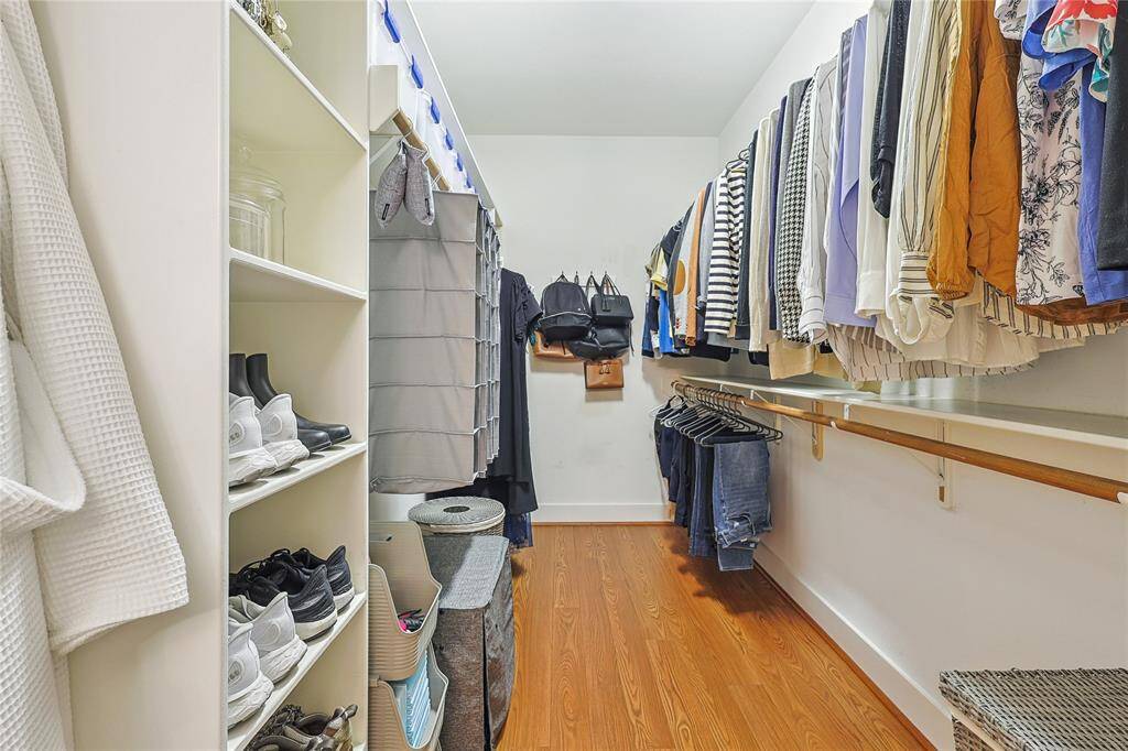 Expansive walk-in closet with custom shelving and hardwood floors.