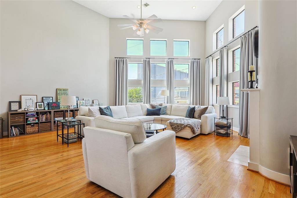 Sunlit living room with high ceilings and a wall of windows for abundant natural light.