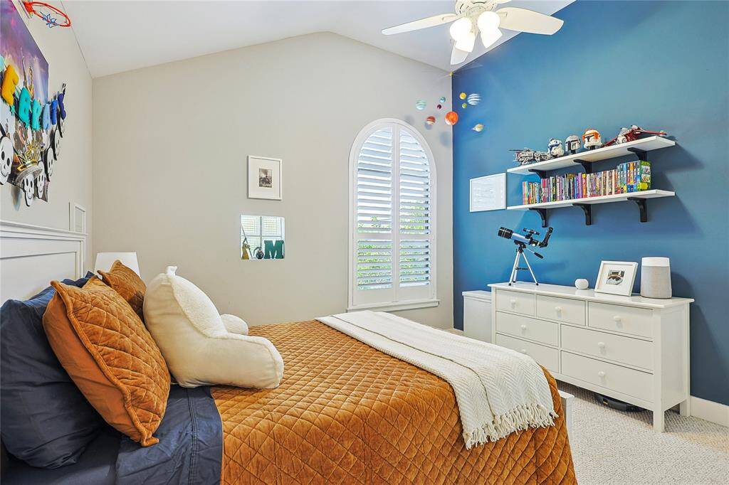 Charming bedroom with vaulted ceiling, accent wall, and arched window for natural light.
