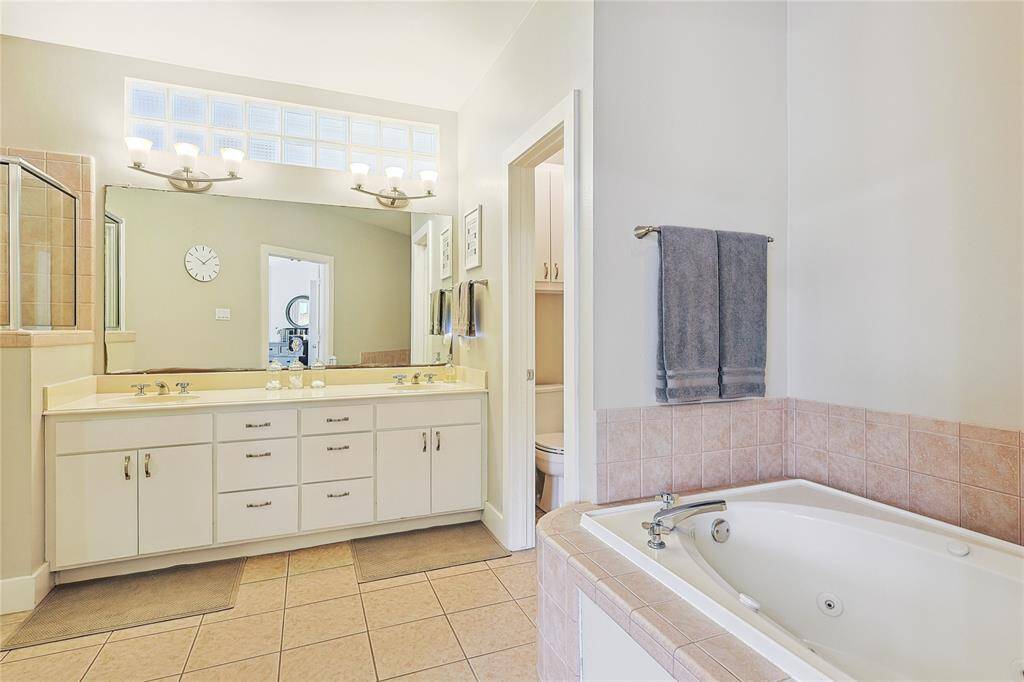 Primary bathroom featuring dual vanities, ample storage, and elegant tile flooring.
