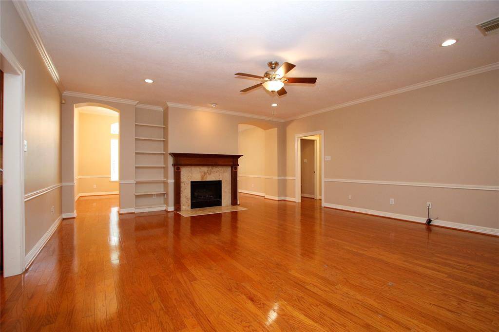 Details abound in this living space with a cozy fireplace,  wood mantel & marble surround.  Custom built-in shelving for displaying your treasures.  Recessed lighting, and neutral walls provide a bright, inviting atmosphere. The hall door to the right in photo provides access to the three secondary bedrooms/ two full bathrooms.  Great split floorplan.