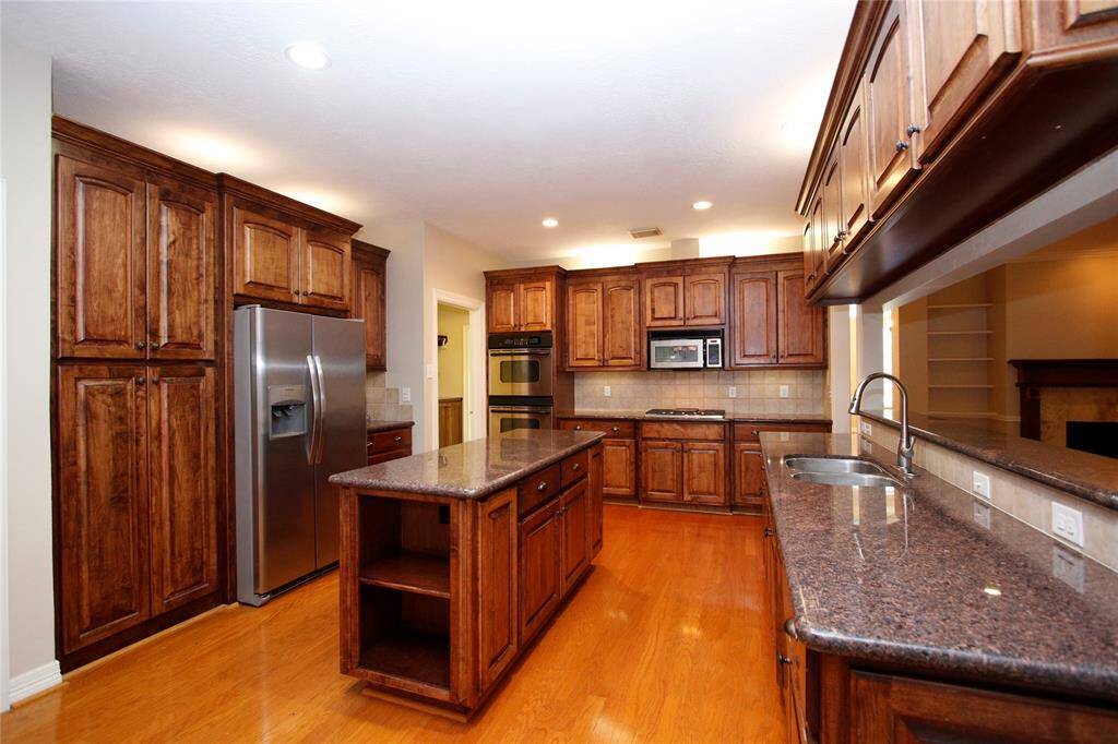 WOW!  Spacious kitchen with rich custom cabinetry, Many pull out drawers for easy access, granite countertops & central island with storage and shelving on both ends.