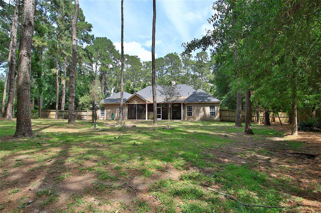 A look from the back of the fully fenced back yard to the back of the house.  This area has been kept as natural as possible and does also include sprinkler system.