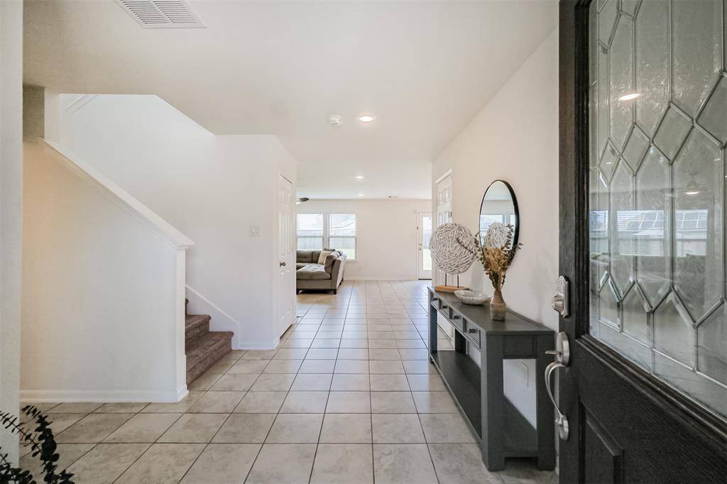 This welcoming entryway features gray tiled flooring and leads to a bright inviting living room.