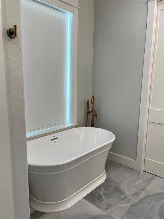 Primary bath tub with window allowing natural light in.