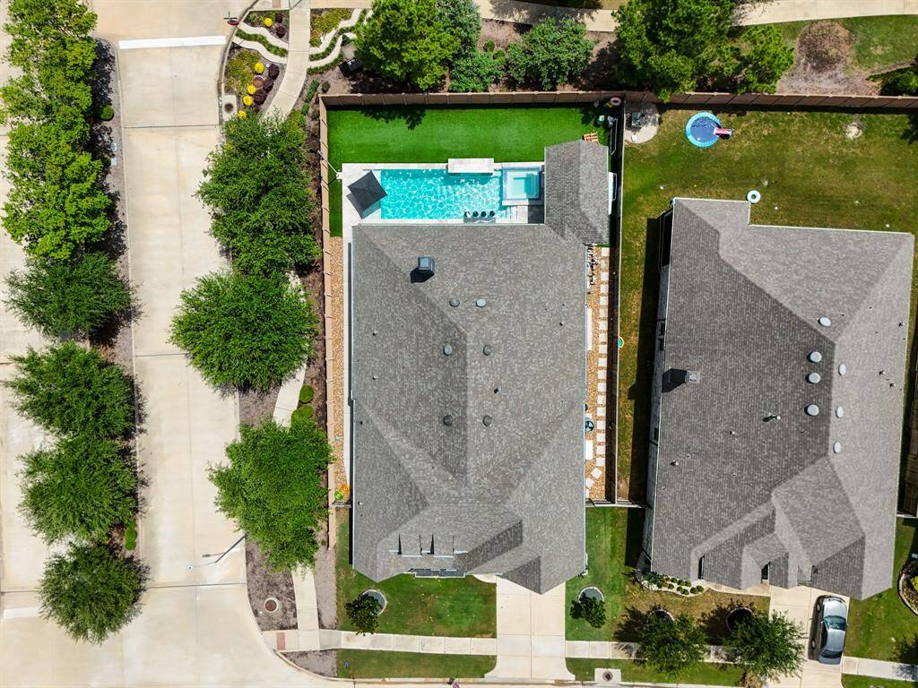 This sweeping aerial shot highlights the spacious corner lot with NO back neighbors, featuring a pool, spa custom landscaping, lush artificial turf, two covered patios, and an outdoor kitchen!